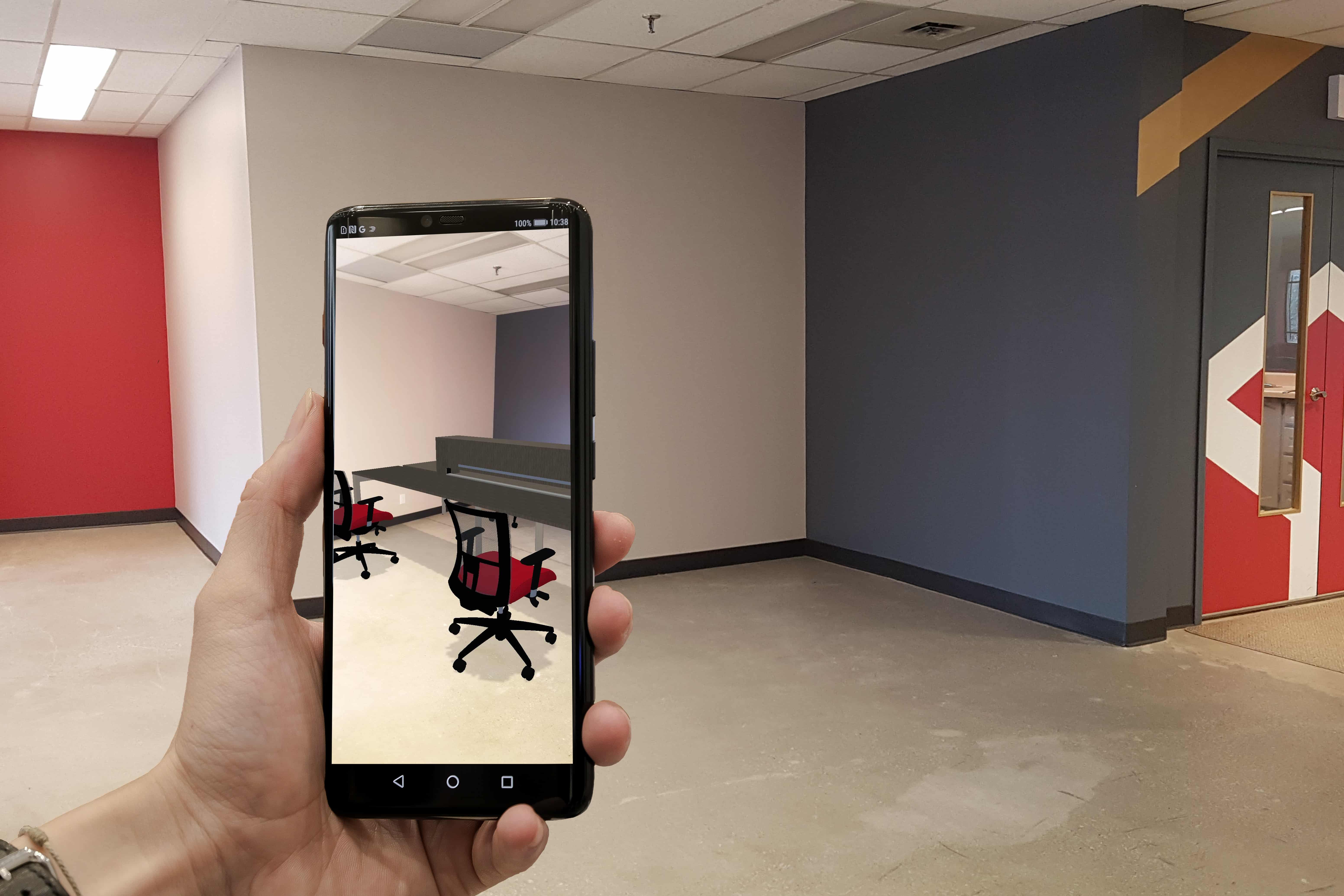 Somone using their phone to view two chairs and a desk in augmented reality. 