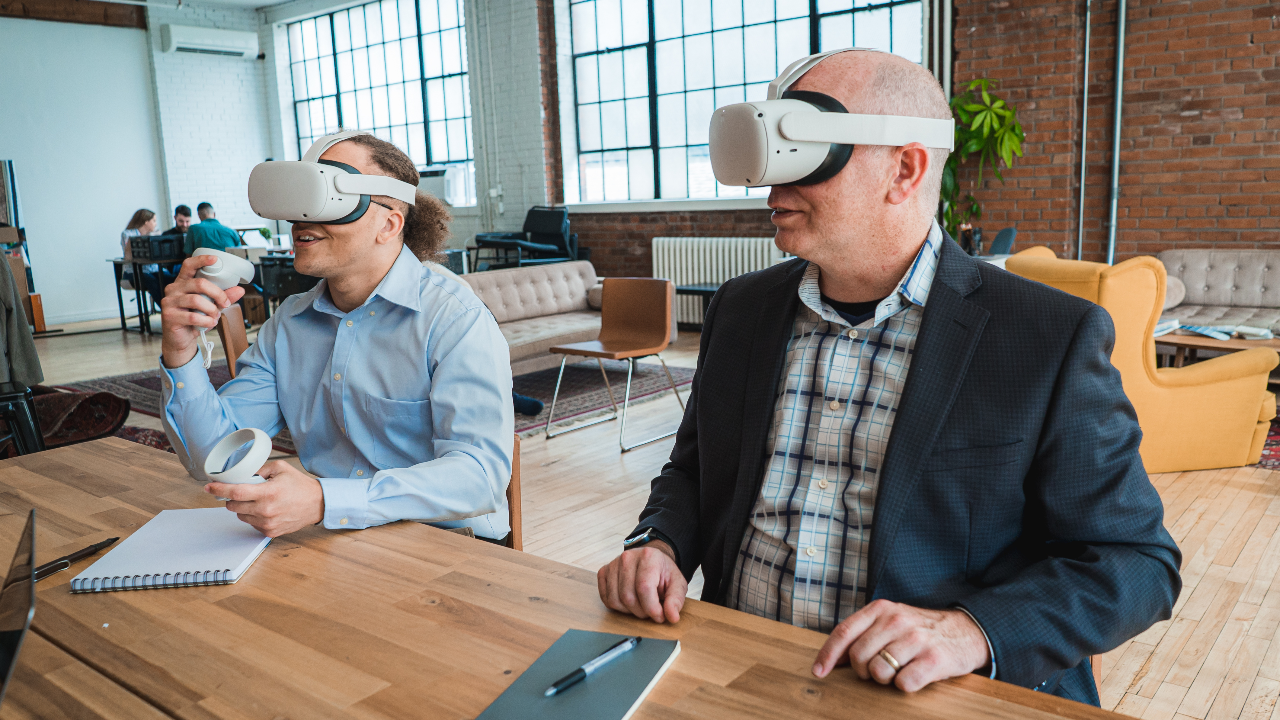 An image of two men using VR headsets. One is holding controllers. 